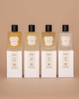 Set of 4 Vellie Wrap Sprays styled on top of packaged boxes. Left to right: Love, Hope, Open and Calm. Made from 100% natural ingredients.