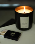 Vellie Calm Candle burning on top of a book in the living room, offering grounding sandalwood and vetiver scents amongst other notes.