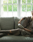 Model in Oat Vellie Wrap sitting on couch reading a book by Brianna Wiest.