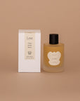 Vellie Love Wrap Spray with all-natural, clean beauty ingredients like lemon, rose, and vanilla oils, designed to enhance the scent and feel of your Vellie baby alpaca wrap. Seen here next its minimal neutral packaged box.