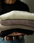 Stack of Vellie Wraps showcasing soft baby alpaca texture. Colors here are Ivory, Mauve, Oat and black.