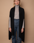 Model wearing black Vellie Wrap in a versatile open style, made from 100% fair-trade baby alpaca fiber, offering exceptional softness and warmth.