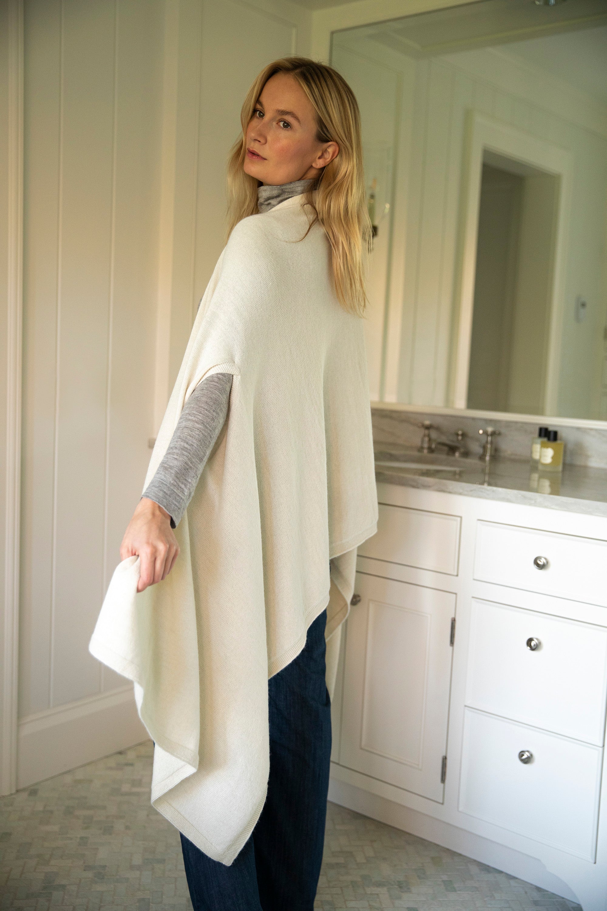 Model showcasing the back of the Vellie ivory wrap, highlighting its cape-like batwing design, crafted from luxurious, 100% fair-trade baby alpaca fiber.