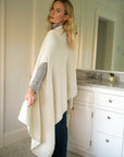 Model showcasing the back of the Vellie ivory wrap, highlighting its cape-like batwing design, crafted from luxurious, 100% fair-trade baby alpaca fiber.