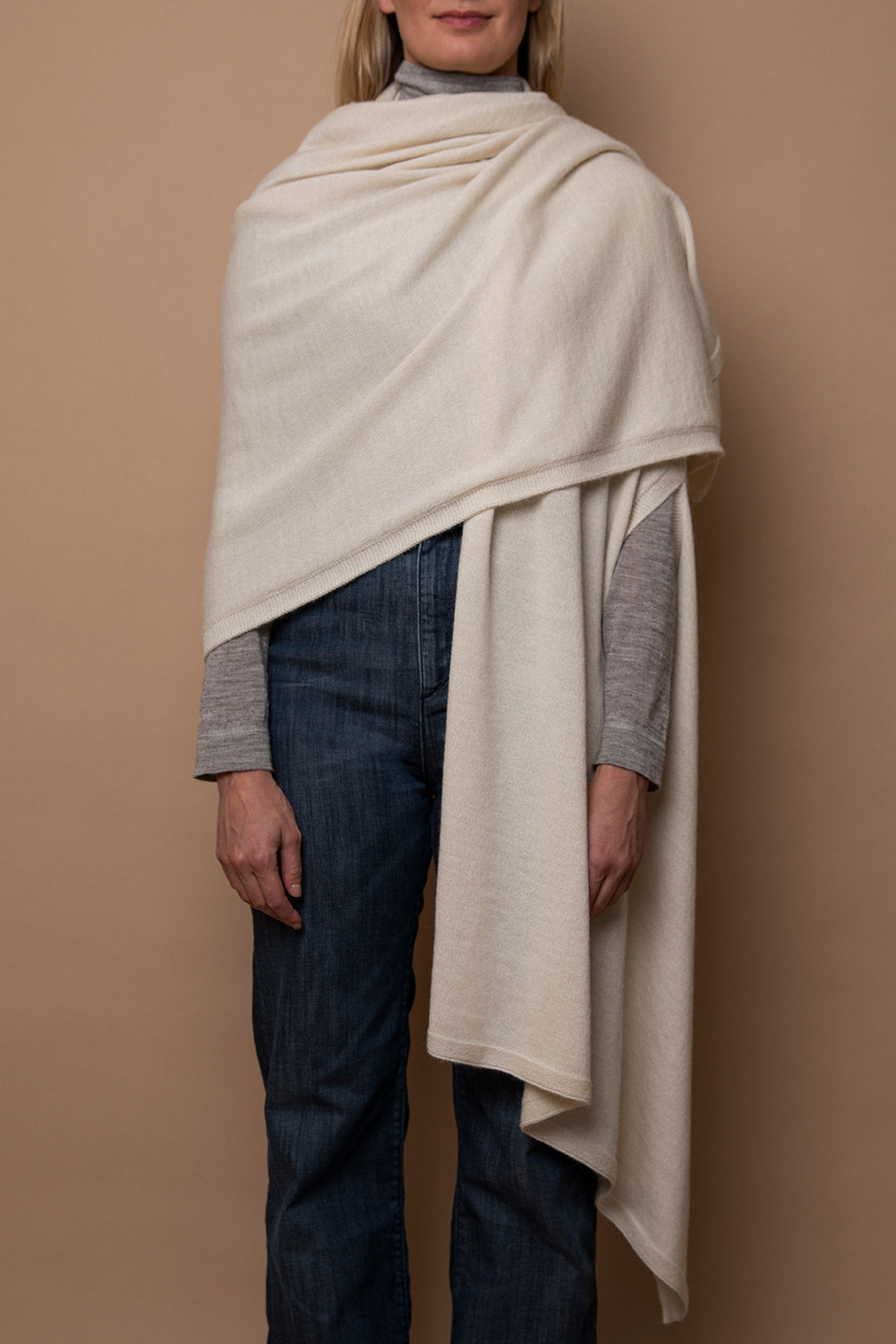 Ivory Vellie wrap draped over one shoulder, crafted from 100% fair-trade baby alpaca fiber for exceptional softness, warmth, and sustainable luxury.