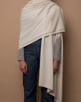 Ivory Vellie wrap draped over one shoulder, crafted from 100% fair-trade baby alpaca fiber for exceptional softness, warmth, and sustainable luxury.