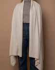 Ivory Vellie wrap worn naturally, showcasing its luxurious 100% fair-trade baby alpaca fiber, offering warmth, softness, and timeless elegance.