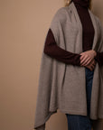 Close-up of oat Vellie wrap in movement, showcasing its beautiful drapery and luxurious texture, crafted from soft, sustainable baby alpaca fiber. Ethically made in Peru.