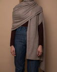 Oat Vellie wrap draped over one shoulder, highlighting its timeless elegance and warmth, made from hypoallergenic, antimicrobial baby alpaca fiber.