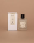 Vellie Wrap Spray in Calm scent next to the packaged box. The spray is showcased in a 3.4 oz bottle, vegan and cruelty-free. It contains a grounding blend of bergamot, lavender, and sandalwood, perfect for enhancing the embrace of your wrap.