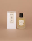 Vellie Wrap Spray in Hope next to neutral pacakged box. The spray is showcased in a 3.4 oz bottle, vegan and cruelty-free. It contains a grounding blend of bergamot, lemon and ylang ylang perfect for enhancing the embrace of your wrap.
