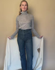 Video of model demonstrating various ways to wear the Vellie ivory wrap, showcasing its versatility as a wrap, scarf, or shawl, made from 100% fair-trade baby alpaca fiber for comfort and style.