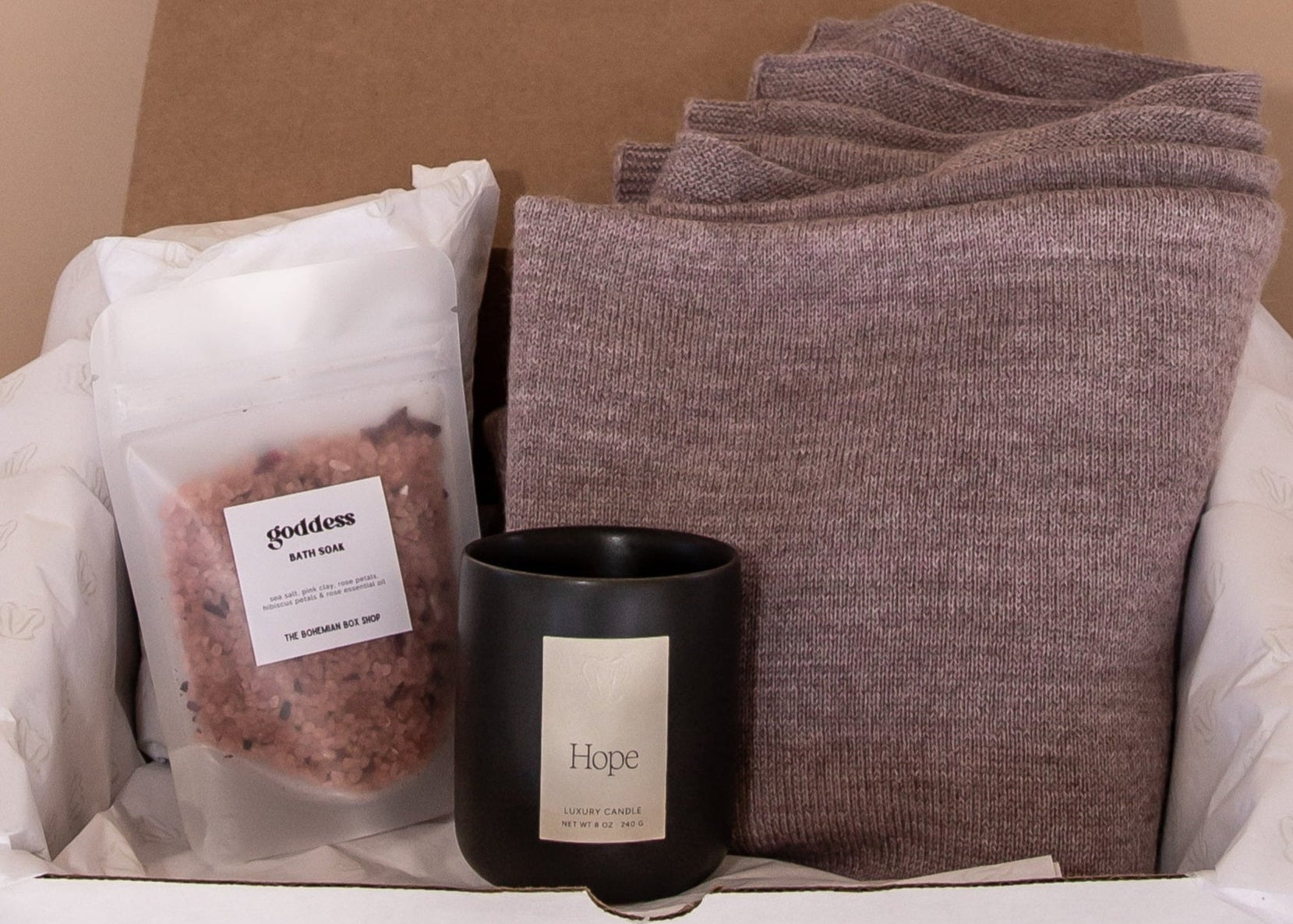 Inside of Imagine Gift Set. Inside, Goddess bath soak by The Bohemian Box Shop, a luxury candle in the scent Hope and a mauve wrap made from ethically sourced baby alpaca.
