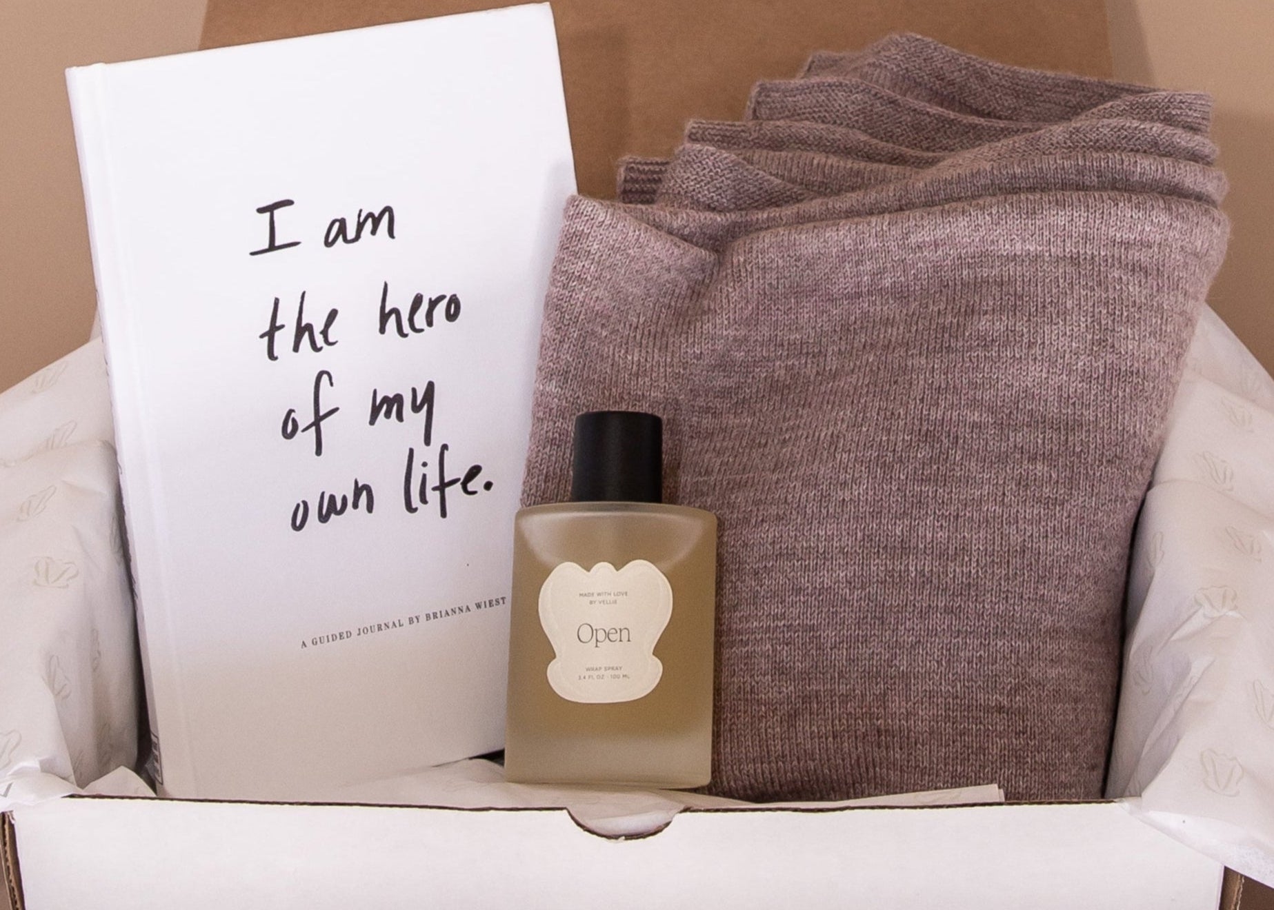 Unboxing of gift bundle, inside is the self-guided journal I am the hero of my own life by Brianna Wiest, a Vellie Wrap Spray in the scent Open and the Mauve Vellie Wrap.