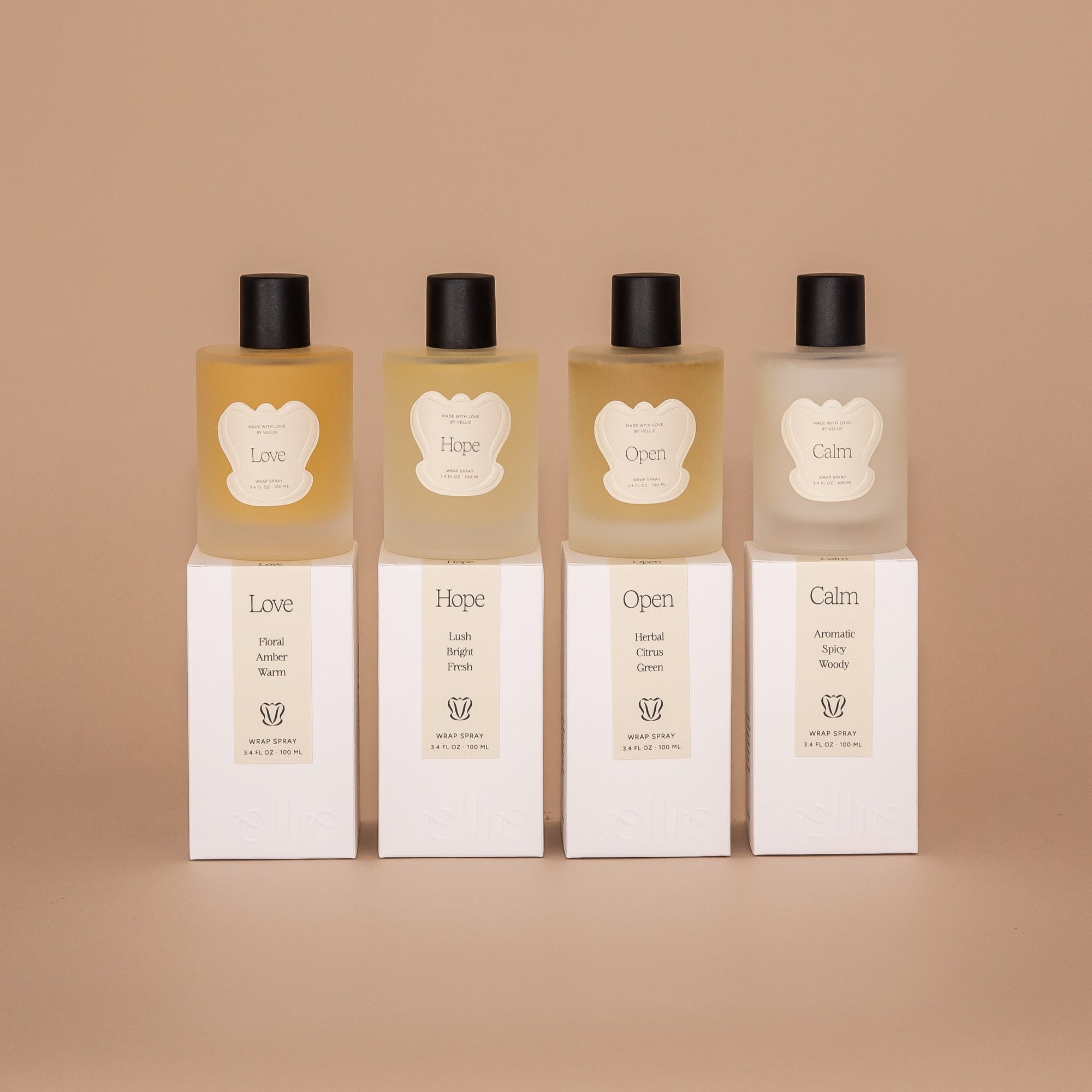 Set of 4 Vellie Wrap Sprays styled on top of packaged boxes. Left to right: Love, Hope, Open and Calm. Made from 100% natural ingredients.