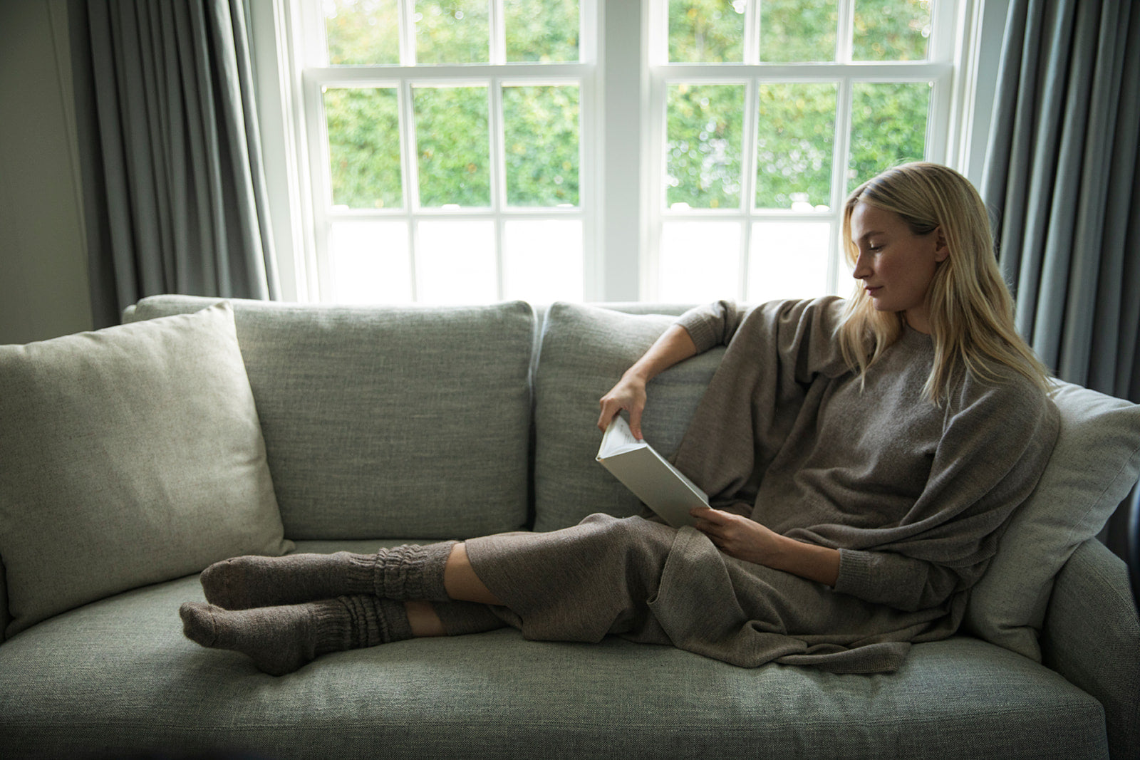 Model in Oat Vellie Wrap sitting on couch reading a book by Brianna Wiest.