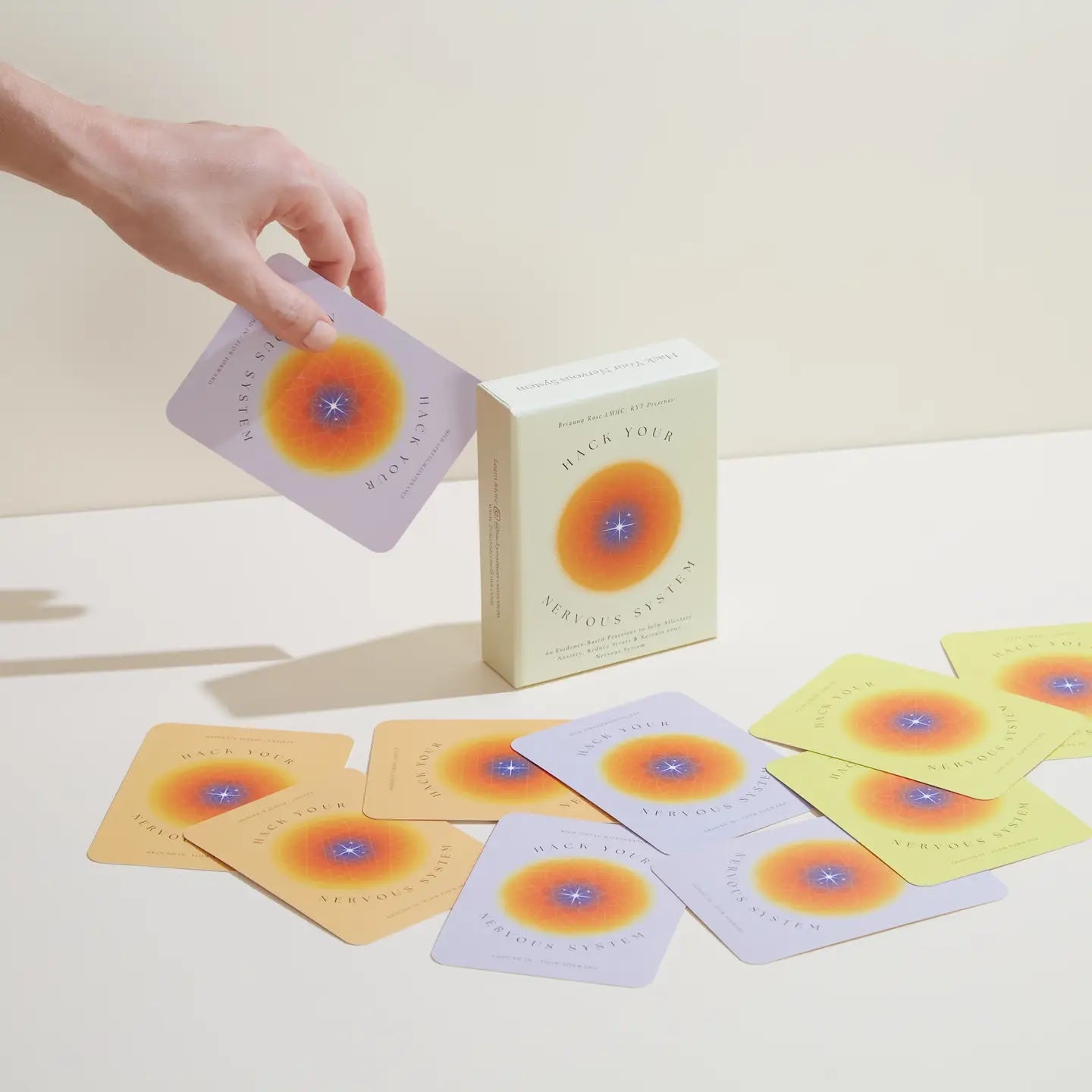 Card deck with colorful circular designs on cards and packaging, on a light surface.