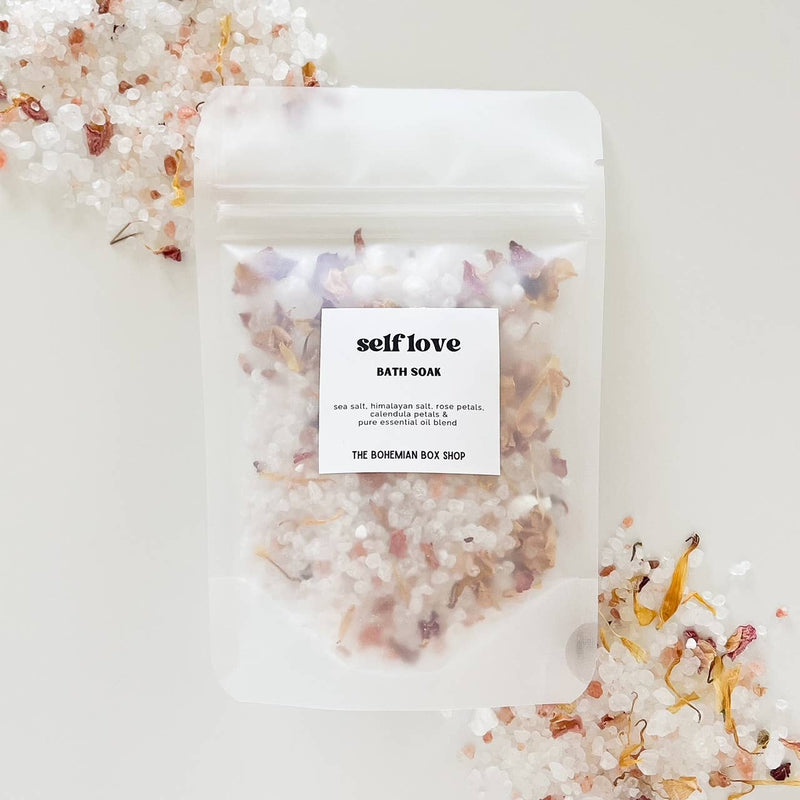 Self Love bath soak by The Bohemian Box Shop. Made in USA all natural ingredients: sea salt, Himalayan salt, rose, petals, calendula petals and pure essential oil blend. Salts are transparent color and light pink with yellow calendula petals.