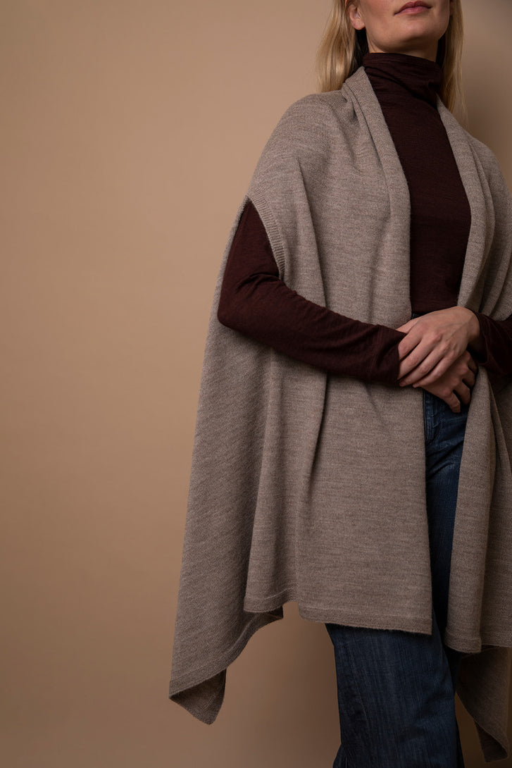 Close-up of oat Vellie wrap in movement, showcasing its beautiful drapery and luxurious texture, crafted from soft, sustainable baby alpaca fiber. Ethically made in Peru.