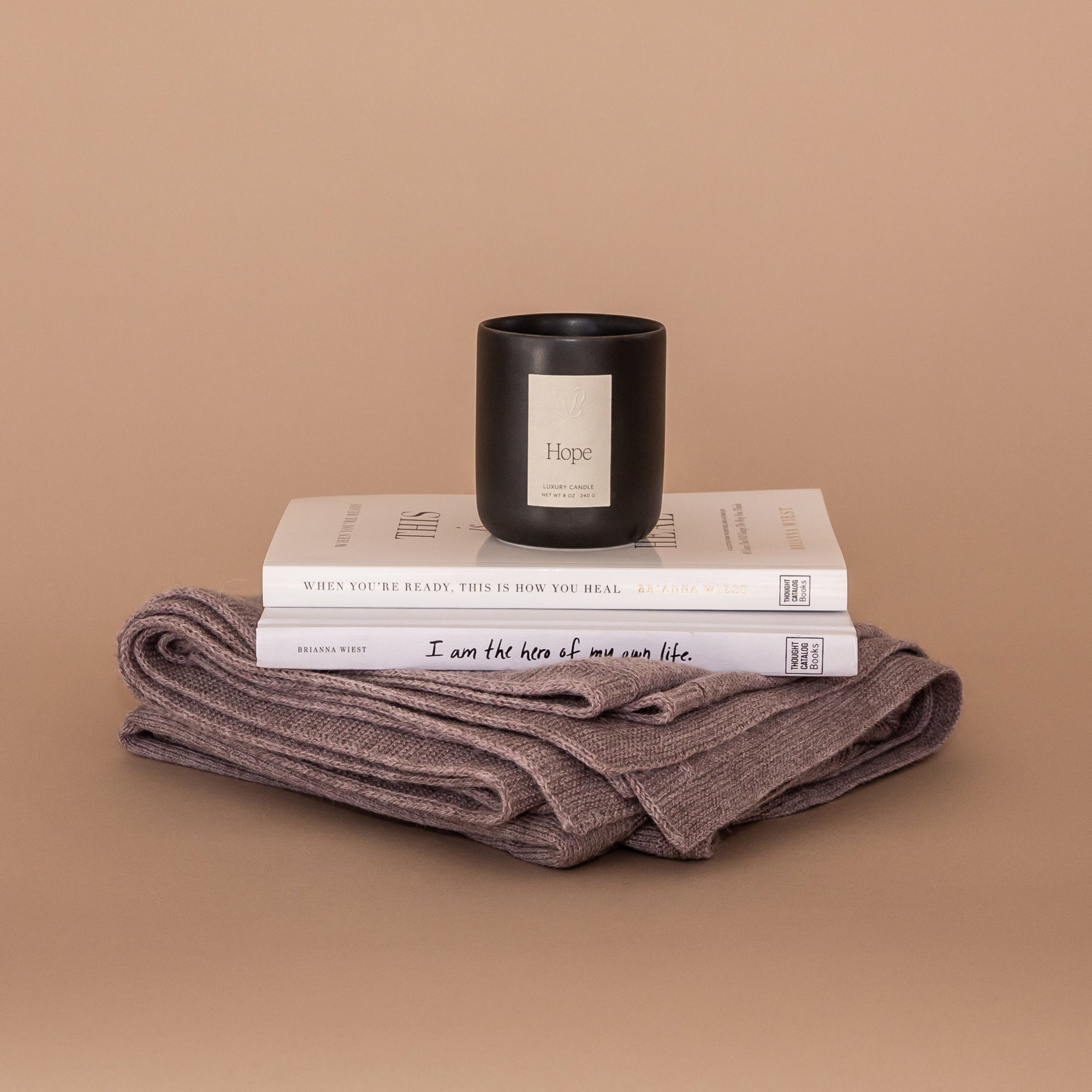 A Lovely Day Gift bundle. Products stacked here: Mauve Vellie Wrap at the bottom, two Brianna Wiest books and a Vellie Candle in the scent Hope.